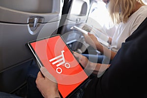 Man holds tablet makes online purchases while sitting in cabin of plane