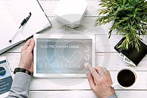 Man holds tablet pc with electric energy usage application