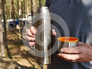A man holds a thermos