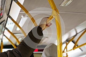 The man holds on to the handrails in a passenger bus.