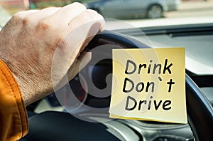 A man holds on to the steering wheel, next to a sticker with the inscription - Drink Do not Drive