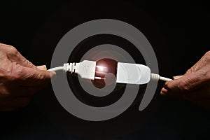 A man holds two disconnected electric cables in his hand on black background. electricity supply problem concept. blackout