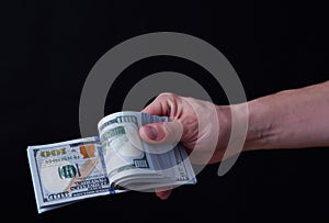 Man holds US dollars in his hand, black background