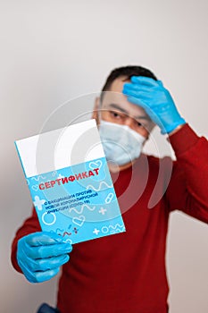 A man holds a vaccination certificate in his hands. Russia, Russian text