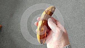 Man holds a very overripe banana in his hand