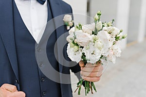 A man holds a wedding bouquet in his hands. The concept of Valentine`s Day and love. Wedding concept