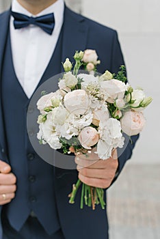 A man holds a wedding bouquet in his hands. The concept of Valentine`s Day and love. Wedding concept