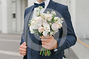 A man holds a wedding bouquet in his hands. The concept of Valentine`s Day and love. Wedding concept