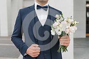 A man holds a wedding bouquet in his hands. The concept of Valentine`s Day and love. Wedding concept