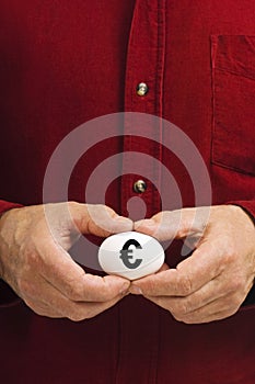 Man holds white egg with Euro symbol written on it