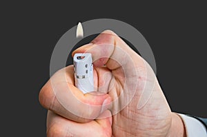 Man holds white lighter in hand and pressing it with thumb
