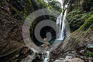 A man holds a woman in his arms at the waterfall. Couple at the waterfall, rear view. Honeymoon trip. Happy couple