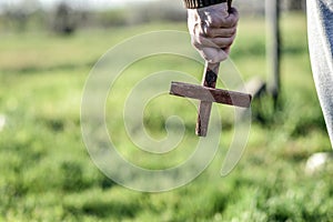 A man holds a wooden Christian cross in front of him, an ax in his other hand. The concept of casting out demons on Halloween