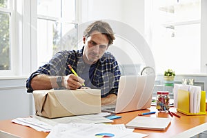 Man At Home Addressing Package For Mailing photo