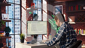 Man at home looking at UI on PC screen, typing and executing programming code
