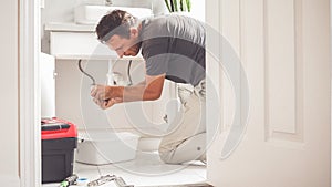 Man At Home Mopping Up Water From Leaking Pipe in Bathroom