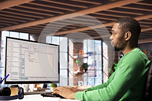 Man in home office looking at PC screen, executing programming code
