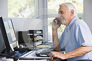 Man in home office on telephone using computer