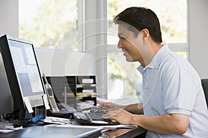 Man in home office using computer and smiling