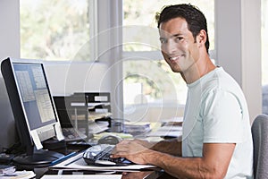 Man in home office using computer and smiling