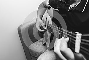 Man at home is playing the guitar. Guys hands are taking the chord on strings. Music making lifestyle concept. Free time hobby for