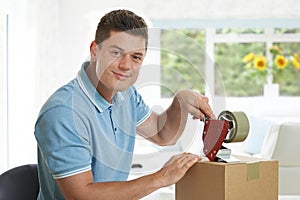 Portrait Of Man At Home Sealing Box For Dispatch