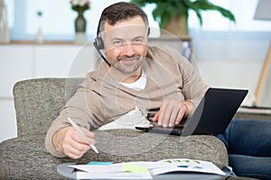 man at home working on laptop and wearing headset
