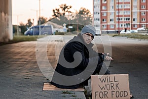 A man, homeless, a man asks for alms on the street with a sign will work for food. Concept of a homeless person, social problem,