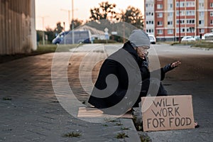 A man, homeless, a man asks for alms on the street with a sign will work for food. Concept of a homeless person, social problem,