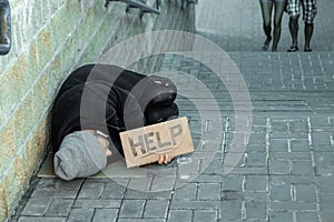 A man, homeless, a person asks for alms on the street with a Help sign. Concept of homeless person, addict, poverty, despair