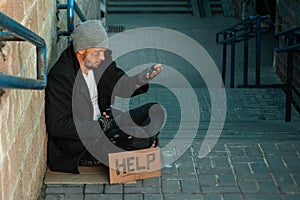 A man, homeless, a person asks for alms on the street with a Help sign. Concept of homeless person, addict, poverty, despair