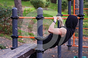 Man in hoodie doing pull-up exercise on bar outdoors