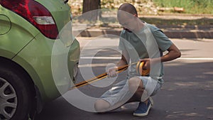 A man hooking a tow rope to a green passenger car.