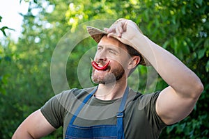 man horticulturist in straw hat with chili pepper vegetable