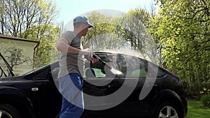 Man, hosing his car at do it yourself car wash, using high pressure water spray