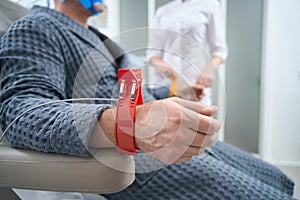 Man in hospital gown sits with sensors on his wrists