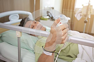 Man in a hospital room calling a nurse. Hand holding emergency button in hospital room