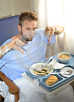 Man in hospital room eating healthy diet clinic food in upset moody face expression