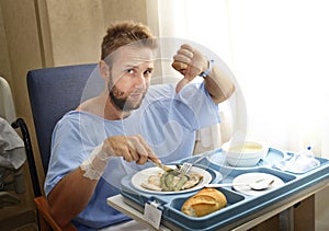 Man in hospital room eating healthy diet clinic food in upset moody face expression