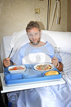 Man in hospital room eating healthy diet clinic food in upset moody face expression