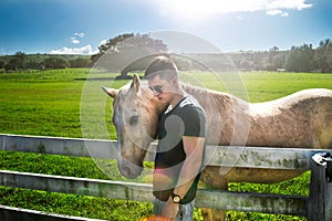 Man hug white horse on rancho farm at sunny summer day. photo