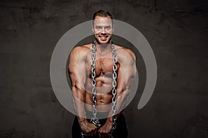 Man with huge biceps and chains posing in studio
