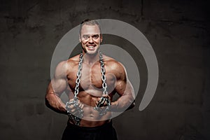 Man with huge biceps and chains posing in studio