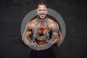 Man with huge biceps and chains posing in studio