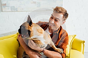 Man hugging french bulldog on sofa