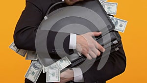 Man hugging his briefcase with sticking out money, corruption, bribe, close-up