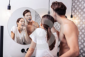 Man hugging his lovely wife while brushing teeth together