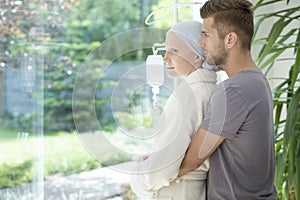 Man hugging sick girlfriend with breast cancer during treatment