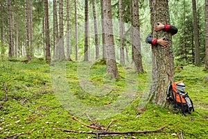 A man hugging a tree in the woods