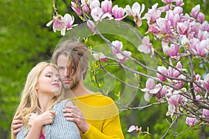 Man hugging woman. Love and romance. Magnolia tree with pink blooming flowers, couple in love, man and woman embrace in